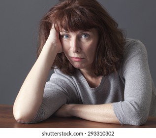 Depressed Mature Woman Resting Her Face On Her Hands Laying Down On A Table For Laziness Or Frustration