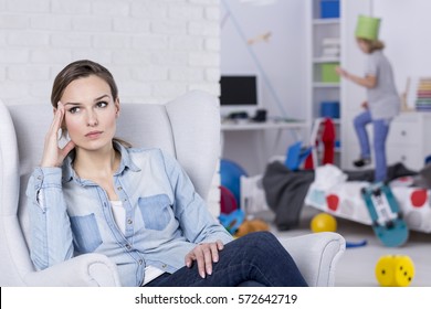 Depressed Mother Of ADHD Boy Sitting In Armchair