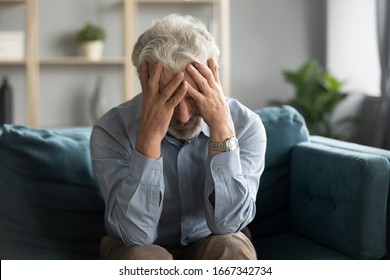 Depressed old 60s man sit on couch in living room feel lonely unhappy mourning yearning at home, stressed sad middle-aged retiree male lost in thoughts miss old times, elderly solitude concept - Powered by Shutterstock