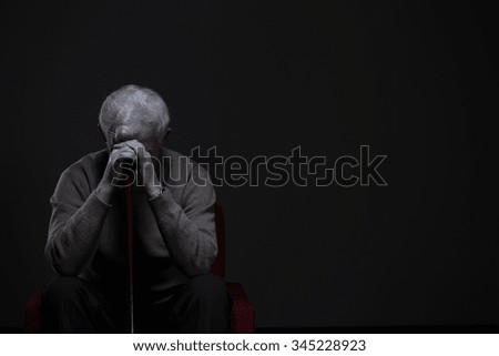 Depressed old man hiding his face behind hands