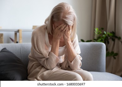 Depressed older woman covering face with hands, crying, feeling desperate. Unhappy mature grandmother experiencing grief, relative’s death, bad news. Stressed elder lady suffering from loneliness. - Powered by Shutterstock