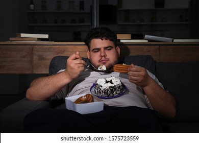 Depressed Overweight Man Eating Sweets In Living Room At Night