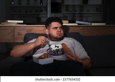 Depressed Overweight Man Eating Sweets In Living Room At Night