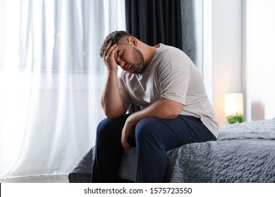 Depressed overweight man on bed at home