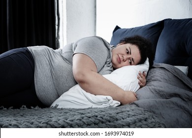 Depressed overweight woman lying alone on bed at home. Autophobia