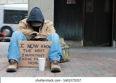 Depressed Panhandler Sitting With A Cup And Sign