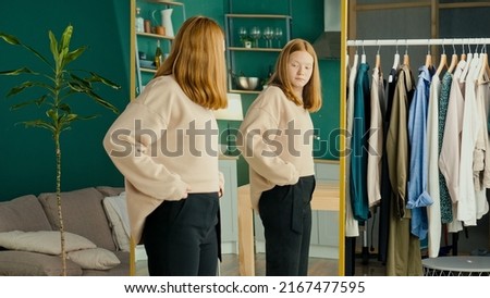 Depressed Red haired Teenage Girl Looking at Her Reflection in the Mirror. Unhappy, Dissatisfied, Insecure Teenager. Concept of Eating Disorder, Anorexia, Bulimia. Mental Health.