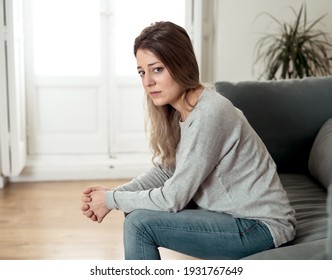 Depressed sad attractive woman crying on sofa couch at home feeling lonely tired and worried suffering depression in mental health, loneliness and isolation concept. Psychology, solitude and people