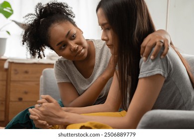 Depressed sad crying woman sitting with friend who support and calm down help and take care in the bad day, Multiracial Asian and African LGBTQ couple relation conflict problem unhappy upset together - Powered by Shutterstock