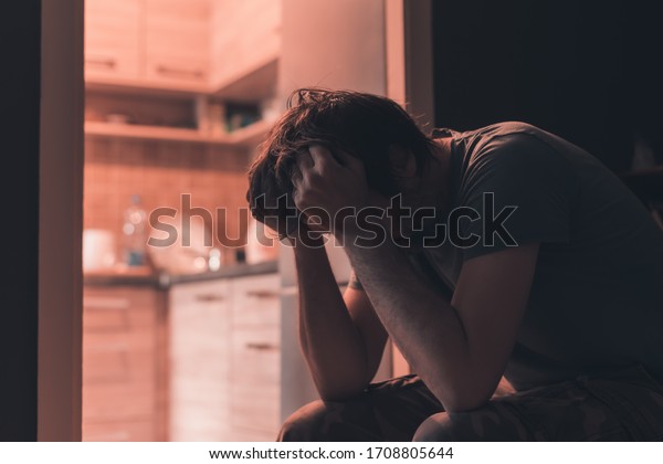 Depressed sad man crying in dark room with head in\
hands, selective\
focus