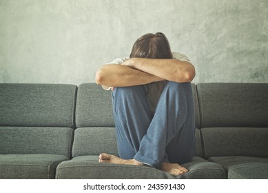 Depressed And Sad Man On The Couch In The Room, Covering Face And Crying In Despair