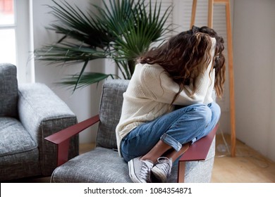 Depressed sad woman holding head in hands sitting on armchair at home, harassment abuse teenage victim feeling bad, heartbroken upset girl crying having mental problem or dangerous drug addiction - Shutterstock ID 1084354871