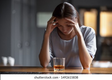 Depressed sad young addicted woman feeling bad drinking whiskey alone in bar, stressed frustrated lonely female drinker alcoholic suffer from alcohol addiction having problem, alcoholism concept