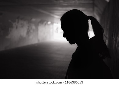 Depressed sad young female standing in a dark tunnel 