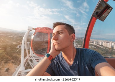 Depressed and sad young man taking selfie while riding ferris wheel in amusement luna park. Loneliness and depression concept
