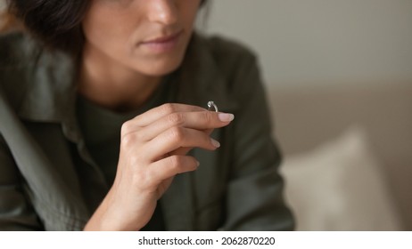 Depressed sad young woman taking off and holding wedding ring. New widow feeling emotional pain, grieving after loss. Divorcee going through depression, apathy, heartbreak crisis. Close up