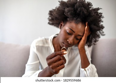 Depressed Sad Young Woman Wife Sit Alone Holding Engagement Wedding Ring In Hand Feeling Upset Disappointed Frustrated Unhappy Regret Marriage Mistake Suffer From Break Up Concept, Close Up View