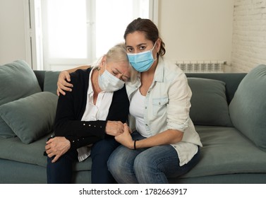 Depressed senior mother and daughter wearing medical mask crying and embracing each other grieving loss of loved ones fighting the Coronavirus. People and families affected by COVID-19 outbreak.