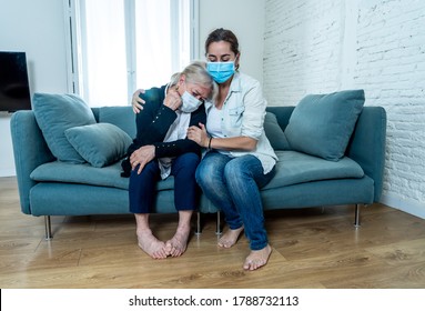 Depressed Senior Mother And Daughter Wearing Medical Mask Crying And Embracing Each Other Grieving Loss Of Loved Ones Fighting The Coronavirus. People And Families Affected By COVID-19 Outbreak.