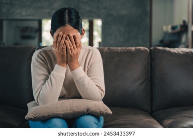 Depressed and Stressed asian woman on sofa. Crying sadness female alone in home problem in life. Unhappy asian woman headache Upset frustrated by problem love relationship feeling despair and anxiety