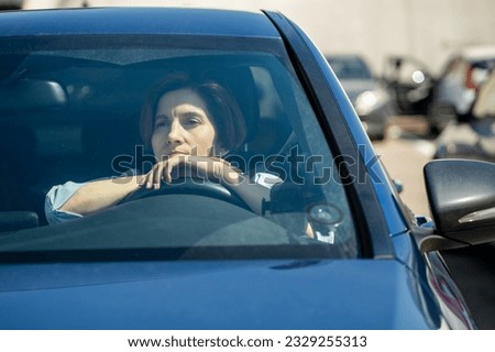 Depressed stressed woman driver sits in car on parking in city. Frustrated confused female thinking about life difficulties, financial problems, sad thoughts, burnout at work, middle aged crisis.