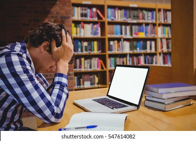 Depressed Student Sitting In Library With Laptop In College