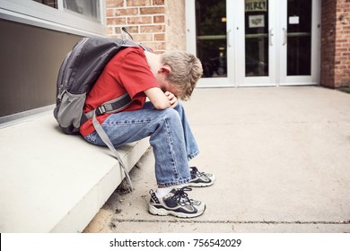 Depressed student sitting outside of school hiding his face - Powered by Shutterstock