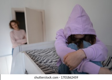 Depressed Teen Girl Wearing Hood Sitting On Bed Ignoring Mother. Sad Teenage Daughter Hiding Problem From Worried Parent Single Mom Having Psychological Trauma After Family Conflict, Divorce Concept.