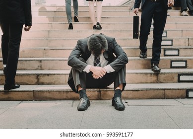 Depressed and tired businessman sitting at stair in city