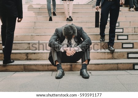 Depressed and tired businessman sitting at stair in city