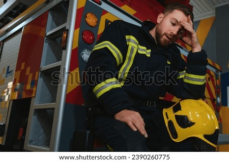 depressed and tired firefighter near fire truck.