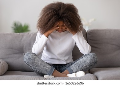 Depressed upset african american teen child girl feeling hurt sitting alone, sad offended lonely black teenage victim cry at home, heartbroken stressed teenager suffer from loneliness abuse bullying