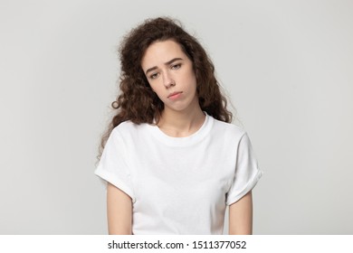 Depressed upset sad millennial woman looking down, feeling frustrated head shot studio portrait. Isolated on grey white background desperate young stressed girl suffering from emotional burnout.