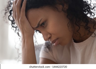 Depressed upset young african american woman holding head in hand feeling lonely abused and hurt, sad heartbroken black girl cry alone at home frustrated about trauma or problem, face close up view