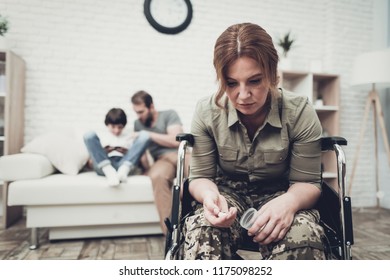 Depressed Veteran Sits In A Wheelchair With Pills. Family Background. Camouflage Uniform. Taking Meds. Disappointed Hero. Paralyzed Soldier. Depression Problem. Posttraumatic Syndrome.