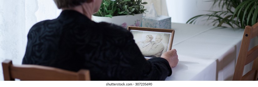 Depressed Widow Looking At Picture With Husband