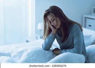 Depressed woman awake in the night, she is touching her forehead and suffering from insomnia