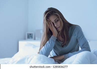 Depressed woman awake in the night, she is touching her forehead and suffering from insomnia