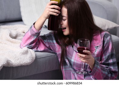 Depressed Woman Drinking Wine Near Sofa Indoors