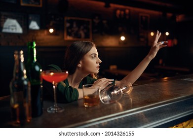 Depressed woman drinks alcohol at counter in bar