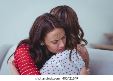 Depressed woman embracing her friend at home