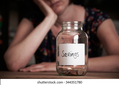 Depressed Woman Looking At Empty Jar Labelled Savings