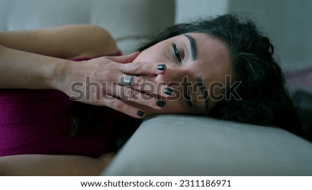 Depressed woman lying on couch. Closeup face of female person in 30s with Sad unhappy expression suffering from emotional distress