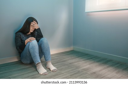 Depressed Woman Overwhelmed By Pandemic Fatigue Sitting On The Floor With Hand On Head