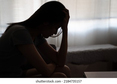 Depressed woman sitting alone on the bed with hands on head feel stress, sad and worried in the dark bedroom and low light environment - Shutterstock ID 2184735157