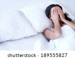 Depressed women in bed. Top view of young sad women lying on the bed and hiding her face in hands