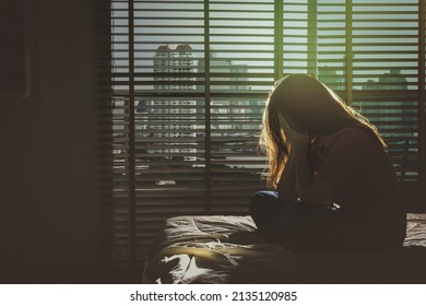 Depressed Women Sitting Head In Hands On The Bed In The Dark Bedroom With Low Light Environment, Dramatic Concept