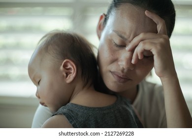 A Depressed Worried Woman At Home Holding Her Baby. Parenting Difficulties.