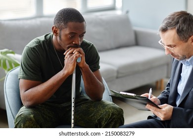 Depressed young adult African American soldier with walking stick treating PTSD with psychotherapy sessions
