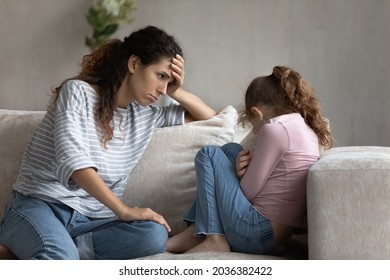 Depressed Young Latin Mother Feeling Guilty Looking At Stressed Little Child Daughter, Having Problems In Communication. Unhappy Different Generations Family Suffering From Relations Troubles.